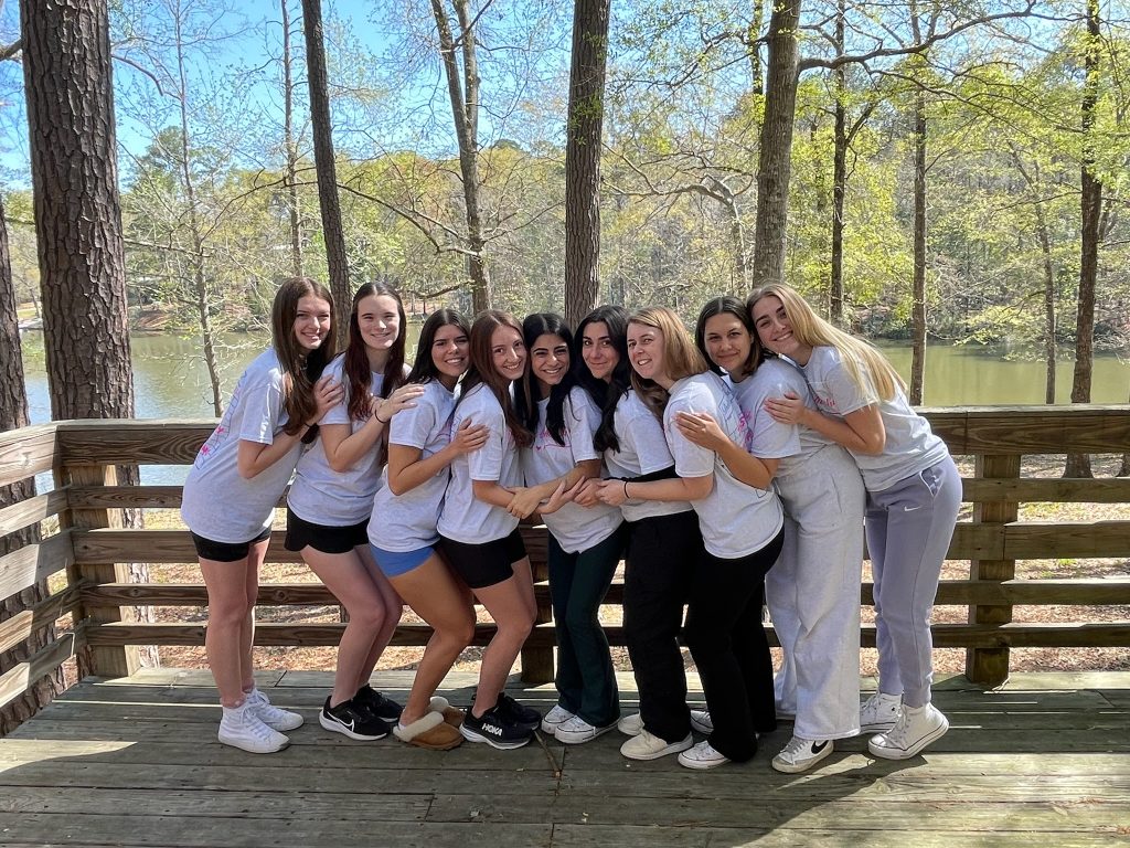 group of girls standing side by side hugging in wooded backdrop